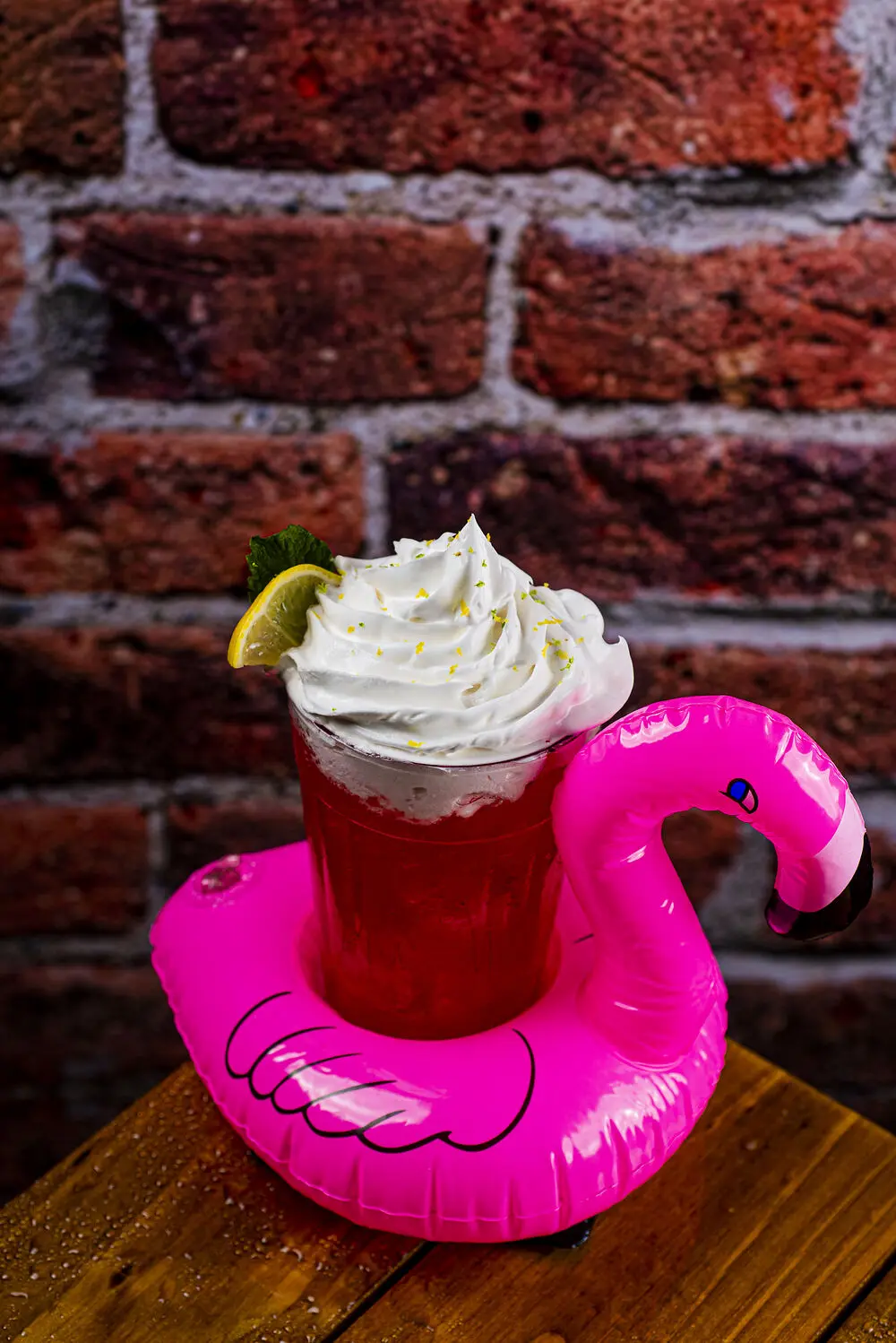 Drink vermelho com chantilly e limão servido na boia de flamingo rosa
