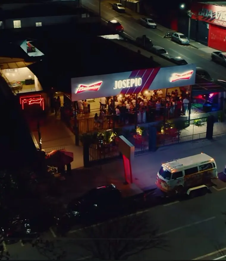 Vista aérea do Josepio Lounge Bar à noite, com a fachada iluminada e o salão cheio